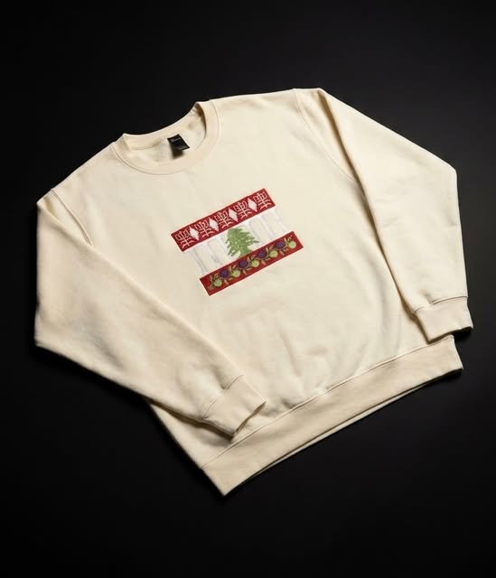 A cream crewneck sweatshirt with colourful embroidered text on a black background.