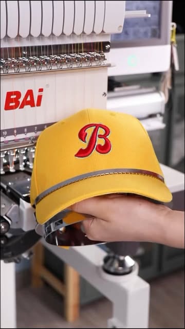 A yellow cap with a red embroidered letter B at the embroidery machine.